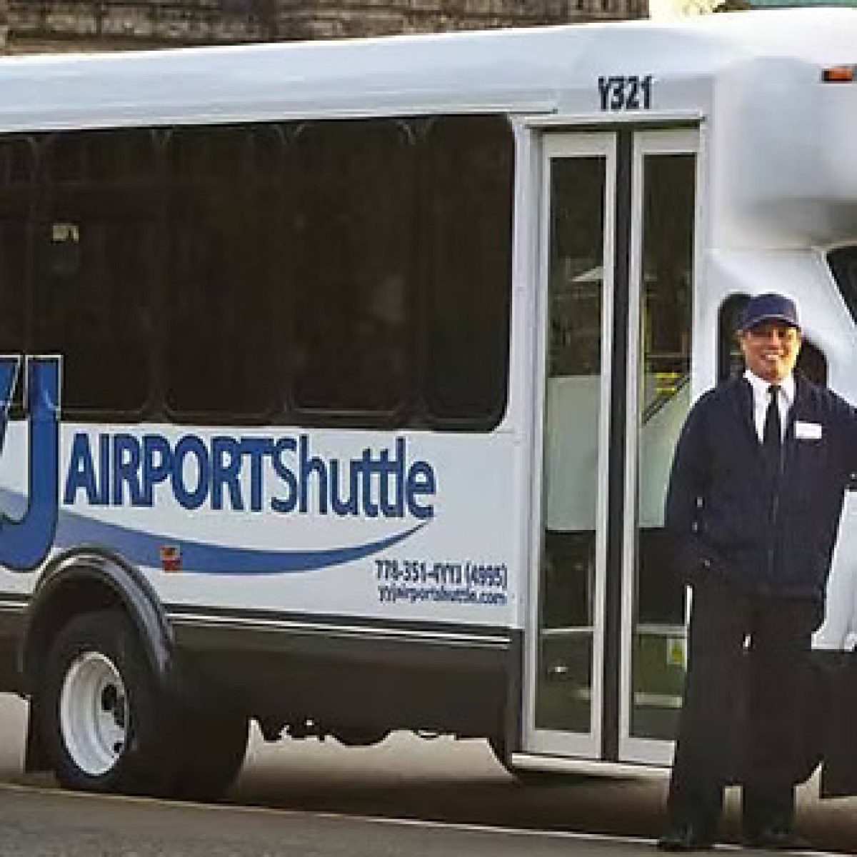 Person in uniform standing beside an airport shuttle bus.