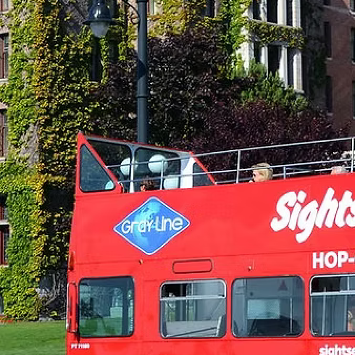 Red double-decker bus in front of an ivy-covered building.