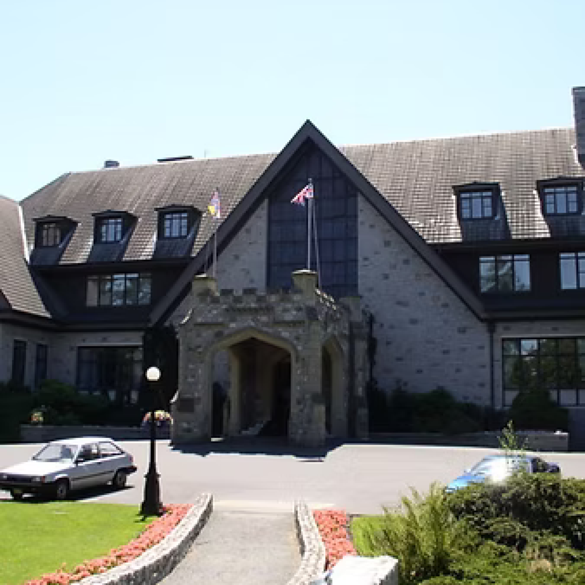 Stone building with steep roof, entrance canopy, and flags.